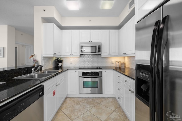 kitchen featuring decorative backsplash, stainless steel appliances, sink, light tile patterned floors, and white cabinets