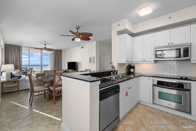 kitchen featuring white cabinetry, sink, kitchen peninsula, decorative backsplash, and appliances with stainless steel finishes