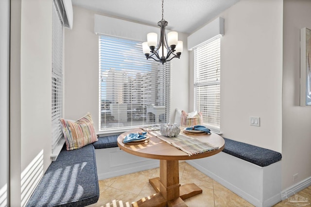 tiled dining area featuring a notable chandelier, breakfast area, and a textured ceiling