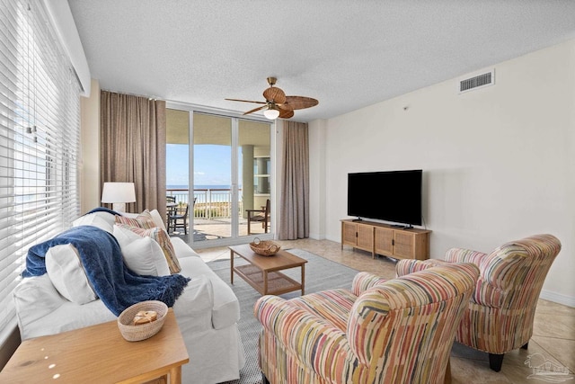 tiled living room featuring a textured ceiling, ceiling fan, and a healthy amount of sunlight