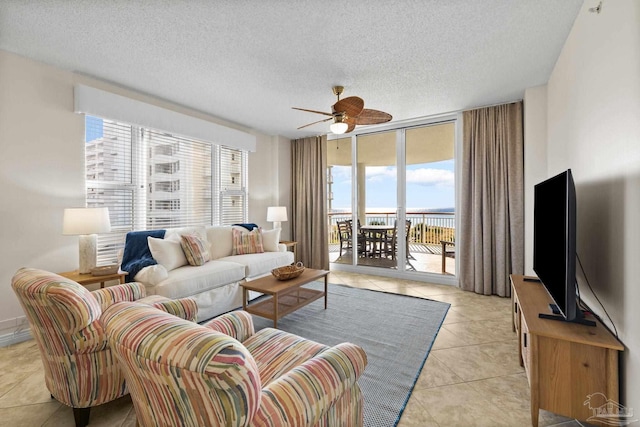 living room featuring ceiling fan, light tile patterned flooring, a textured ceiling, and expansive windows