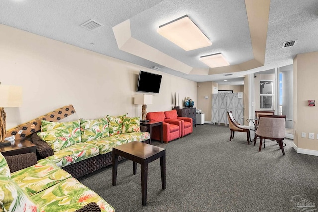 living room with carpet floors, a textured ceiling, and a tray ceiling