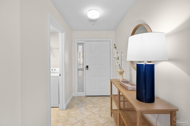 tiled foyer entrance with a textured ceiling and washer / dryer