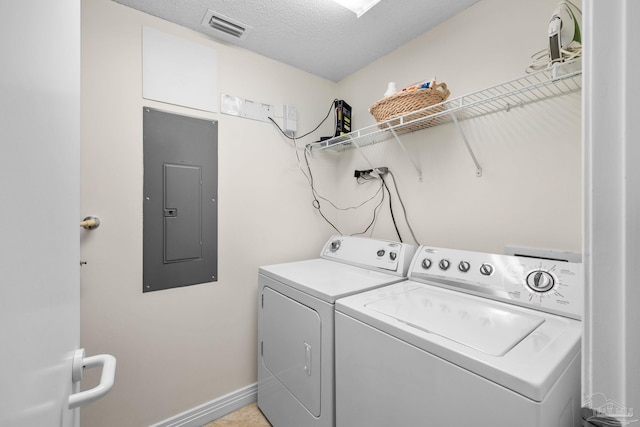 clothes washing area featuring a textured ceiling, electric panel, and washing machine and dryer