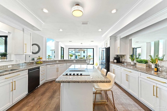 kitchen featuring light stone countertops, kitchen peninsula, white cabinets, and black appliances