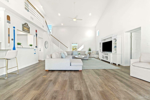 living room with a towering ceiling, hardwood / wood-style floors, and ceiling fan