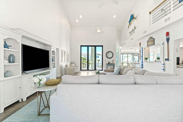 living room with dark hardwood / wood-style flooring, a towering ceiling, and ceiling fan