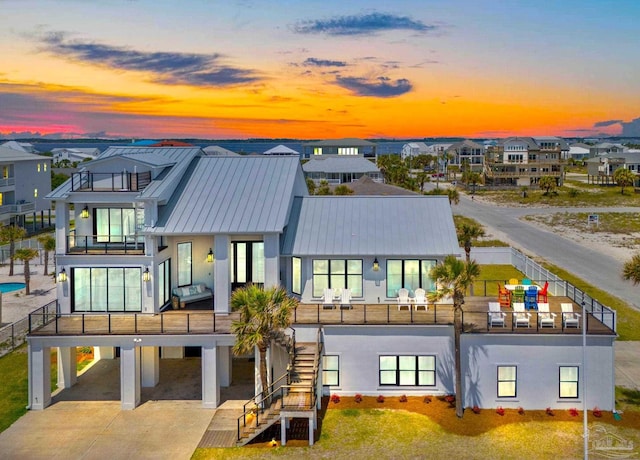 back house at dusk featuring a carport and a balcony