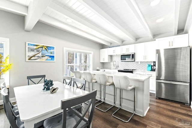 kitchen with appliances with stainless steel finishes, white cabinetry, a breakfast bar area, decorative backsplash, and a center island