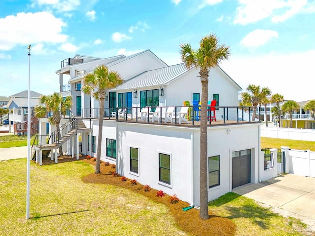 rear view of property with a garage, a balcony, and a lawn