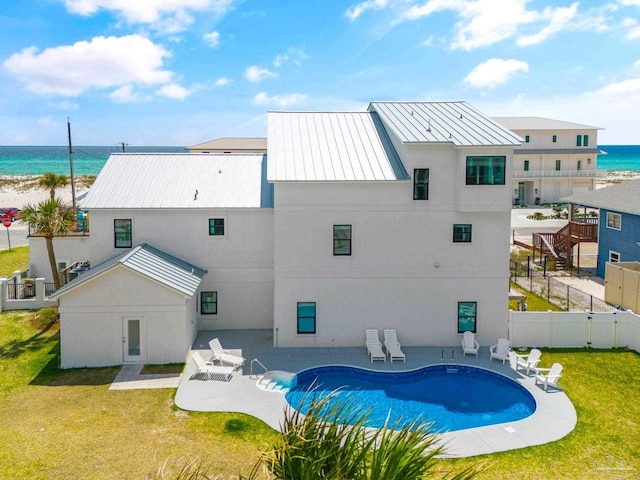 back of property with a fenced in pool, a patio, a water view, and a lawn