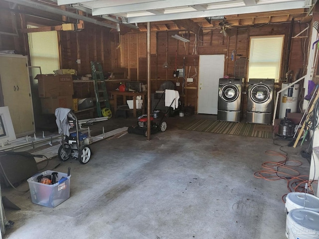 garage with electric water heater, wood walls, and independent washer and dryer