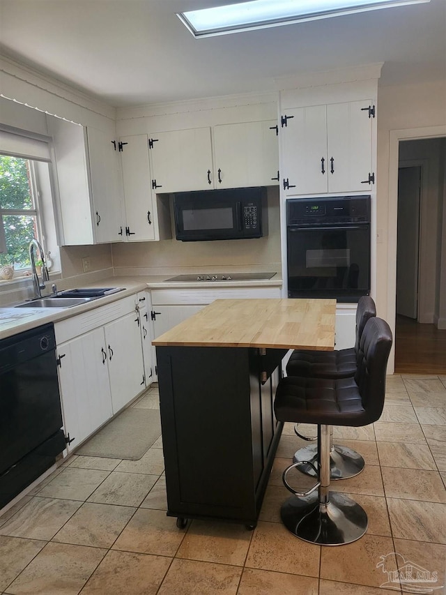 kitchen featuring sink, white cabinetry, black appliances, a kitchen breakfast bar, and a center island