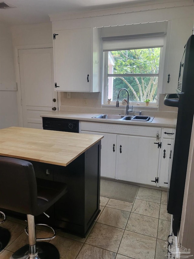 kitchen featuring decorative backsplash, white cabinets, fridge, and sink