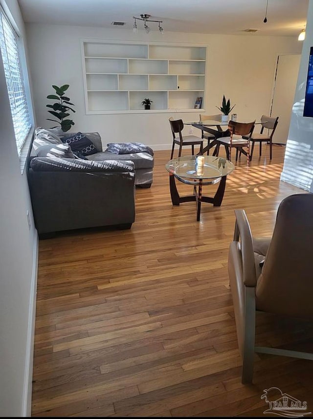 living room with built in shelves and hardwood / wood-style floors