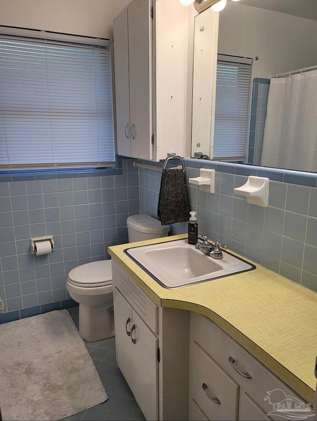 bathroom featuring tile walls, vanity, toilet, and tile patterned floors