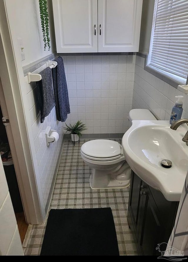 bathroom featuring vanity, tile walls, and toilet