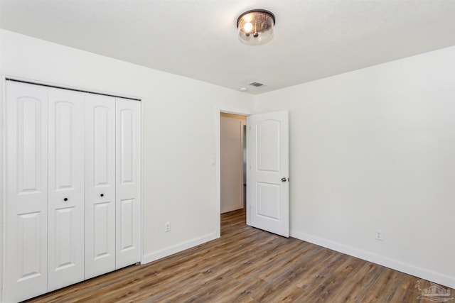 unfurnished bedroom with wood-type flooring and a closet