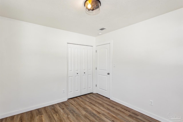 unfurnished bedroom with a closet and wood-type flooring