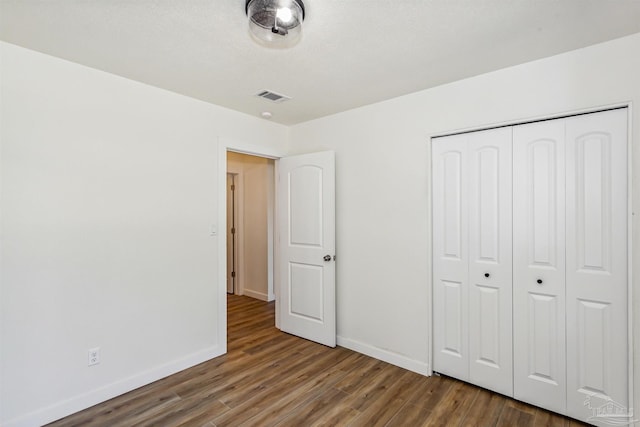 unfurnished bedroom with a closet and dark hardwood / wood-style flooring