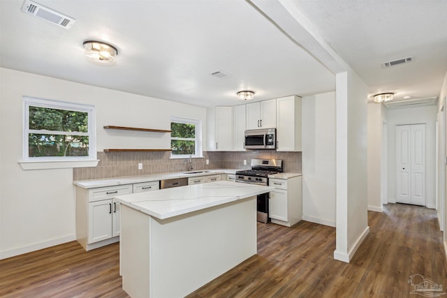 kitchen with a kitchen island, appliances with stainless steel finishes, white cabinets, and dark hardwood / wood-style flooring