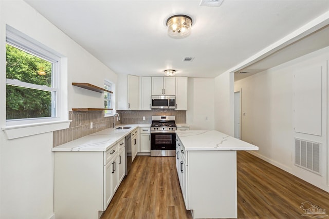 kitchen featuring tasteful backsplash, dark hardwood / wood-style flooring, appliances with stainless steel finishes, white cabinetry, and a center island