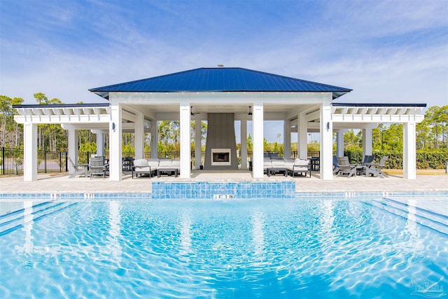 pool featuring a patio, ceiling fan, fence, an outdoor living space with a fireplace, and a pergola