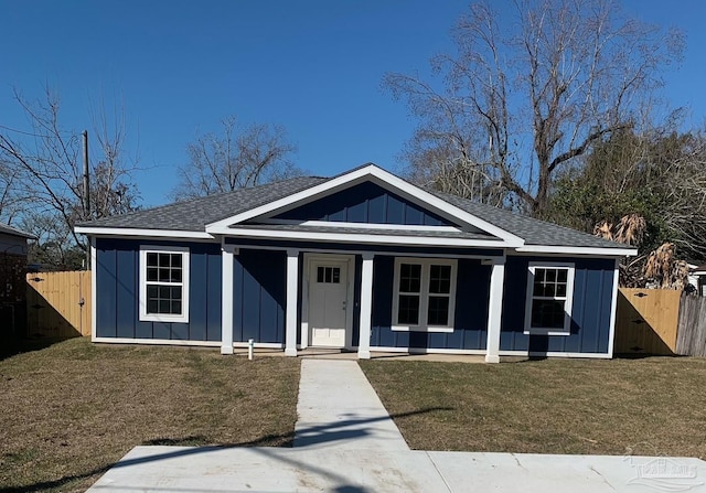 bungalow-style house featuring board and batten siding, a front yard, roof with shingles, and fence