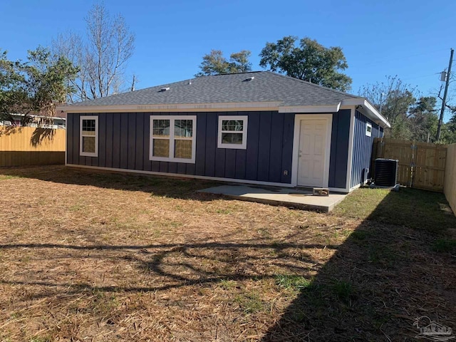 rear view of property featuring a fenced backyard, a lawn, board and batten siding, and roof with shingles