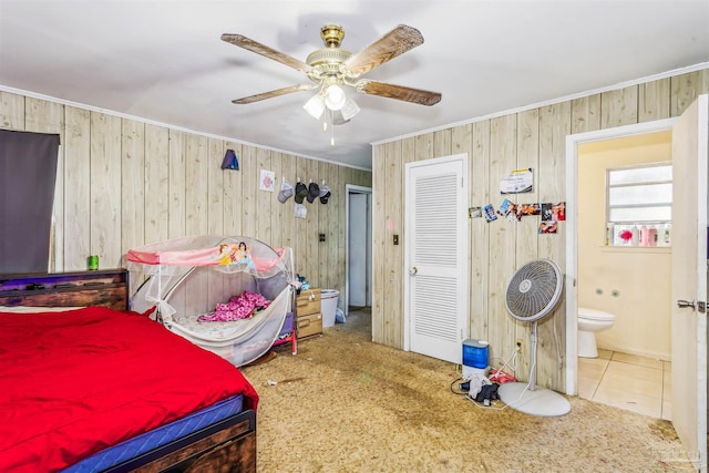 bedroom with crown molding, wood walls, ceiling fan, and carpet flooring