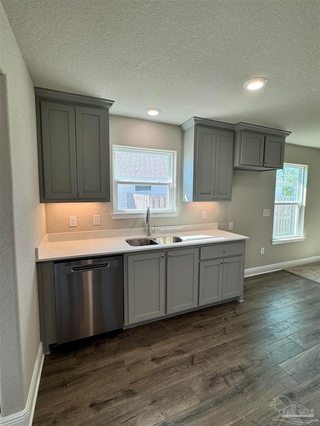 kitchen with dark wood-type flooring, stainless steel dishwasher, sink, and gray cabinetry