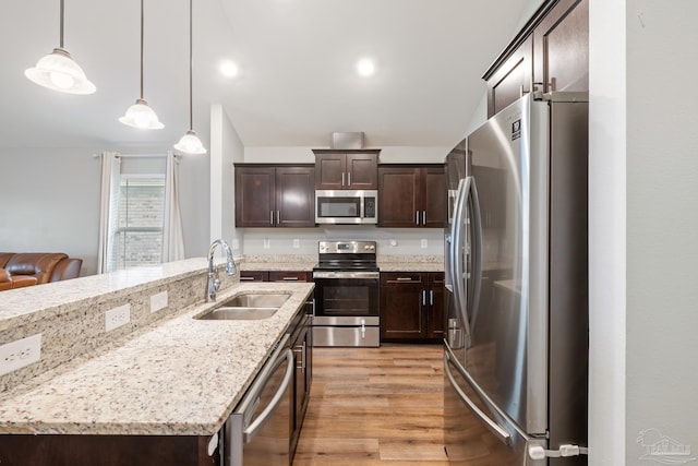 5726 Dunridge Dr, Pace, FL 32571 - kitchen featuring stainless steel appliances, a sink, dark brown cabinets, light wood-style flooring, and decorative light fixtures