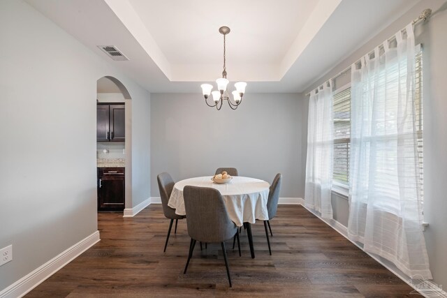 5726 Dunridge Dr, Pace, FL 32571 - dining space with a raised ceiling, a chandelier, dark wood finished floors, baseboards, and arched walkways