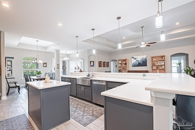 kitchen with a large island, a raised ceiling, sink, and hanging light fixtures