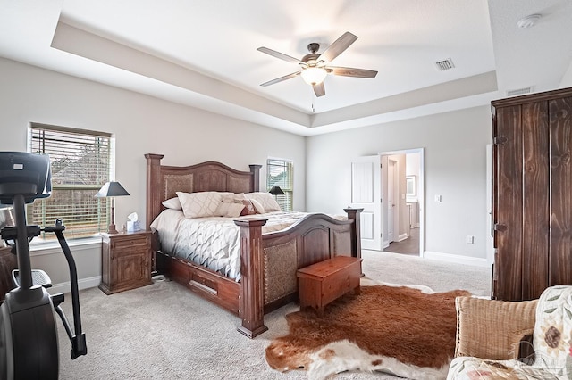 carpeted bedroom featuring ceiling fan and a tray ceiling