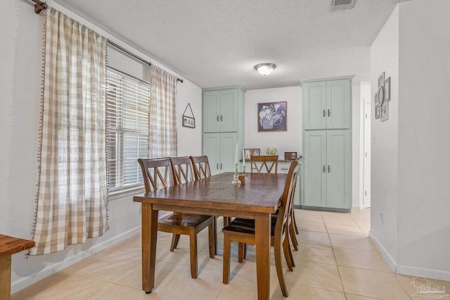 dining room with a textured ceiling, baseboards, and light tile patterned floors