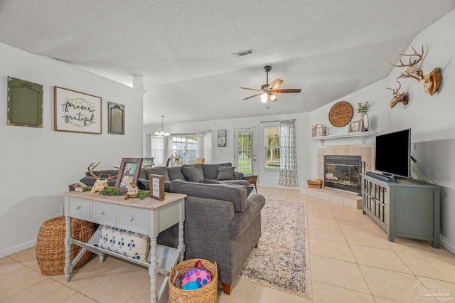 living room featuring vaulted ceiling, light tile patterned floors, visible vents, a ceiling fan, and a fireplace