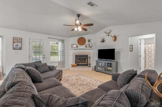 living room with visible vents, a fireplace, a ceiling fan, lofted ceiling, and light tile patterned floors