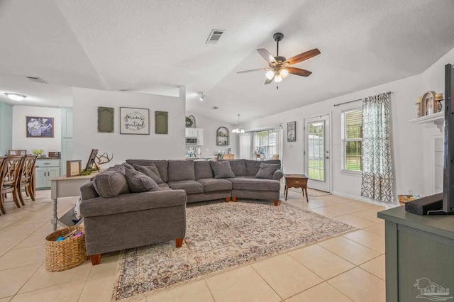 living area with a textured ceiling, lofted ceiling, light tile patterned floors, ceiling fan with notable chandelier, and visible vents