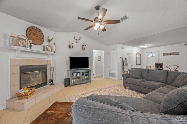 tiled living area with a ceiling fan, a fireplace, a textured ceiling, lofted ceiling, and visible vents