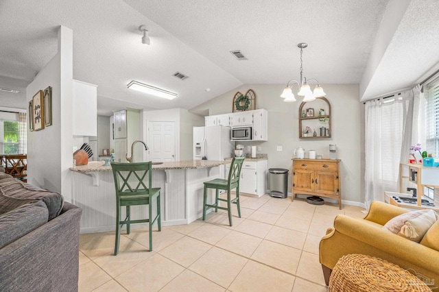 kitchen featuring open floor plan, stainless steel microwave, white refrigerator with ice dispenser, visible vents, and a peninsula
