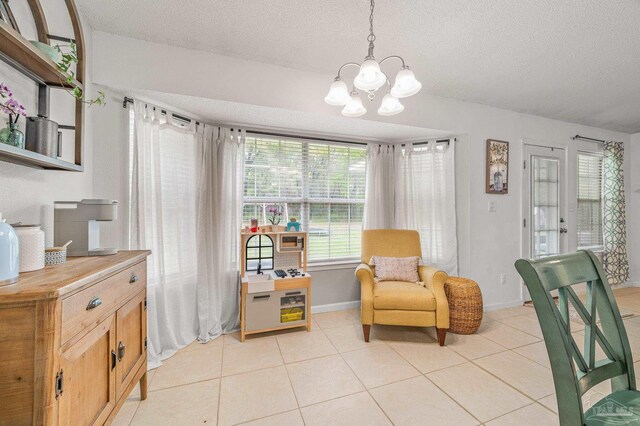 living area with a textured ceiling, a notable chandelier, baseboards, and light tile patterned floors