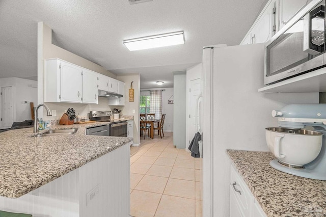 kitchen with light tile patterned flooring, a sink, under cabinet range hood, stainless steel appliances, and white cabinets
