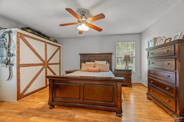 bedroom featuring baseboards, a textured ceiling, ceiling fan, and light wood-type flooring