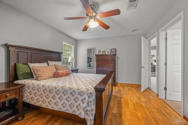 bedroom with baseboards, visible vents, light wood-type flooring, and a textured ceiling