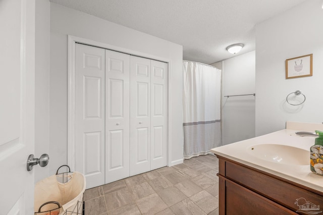 bathroom with a closet, curtained shower, a textured ceiling, and vanity