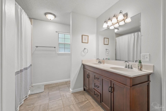 full bath featuring double vanity, baseboards, a sink, and a textured ceiling