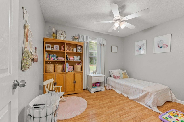 bedroom featuring light wood finished floors, ceiling fan, and a textured ceiling