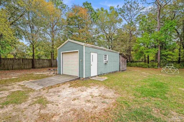 detached garage featuring fence and concrete driveway