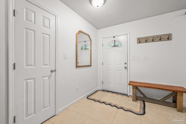 foyer featuring light tile patterned flooring, a textured ceiling, and baseboards